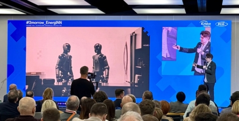 Petros Psyllos podczas wystąpienia na konferencji 2morrow EnergINN, na ekranie roboty humanoidalne